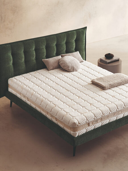 Materasso Befresh Air posizionato su un letto in ambiente neutro con sopra cuscini e scaldapiedi warmie