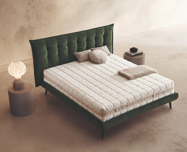 Materasso Befresh Air posizionato su un letto in ambiente neutro con sopra cuscini e scaldapiedi warmie