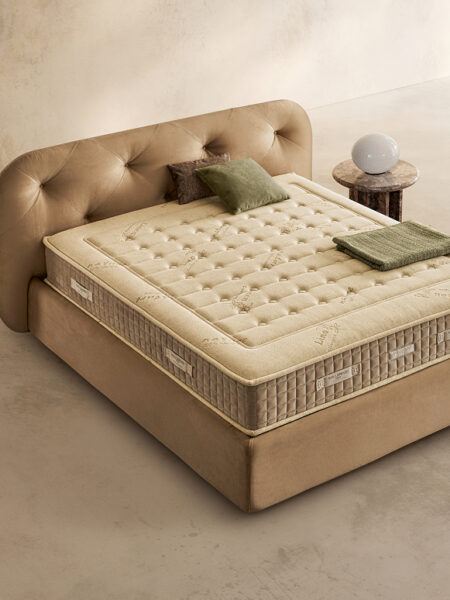 Materasso Green Bio Mind posizionato su un letto in ambiente neutro con sopra cuscini e scaldapiedi warmie