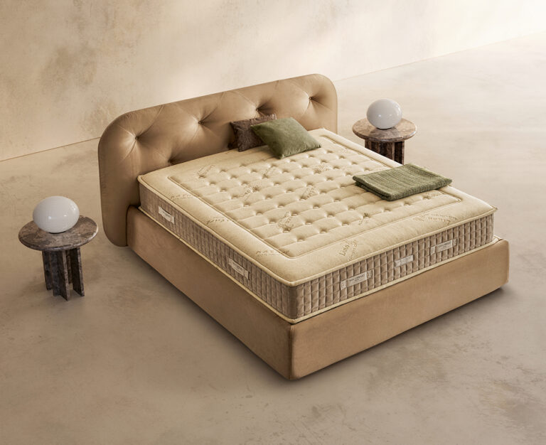 Materasso Green Bio Mind posizionato su un letto in ambiente neutro con sopra cuscini e scaldapiedi warmie