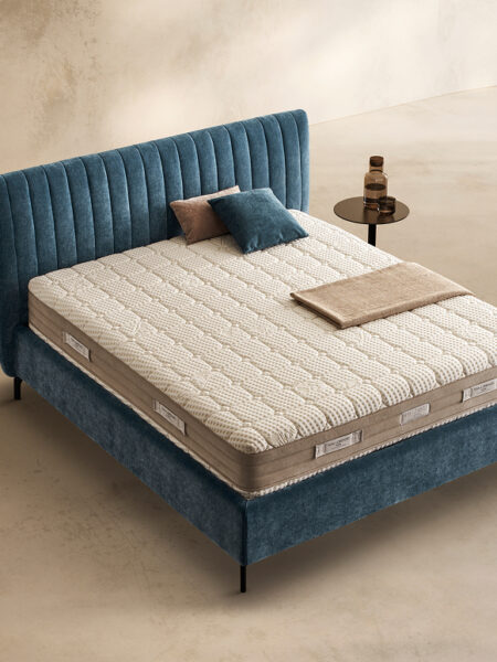 Materasso Medical Form posizionato su un letto in ambiente neutro con sopra cuscini e scaldapiedi warmie