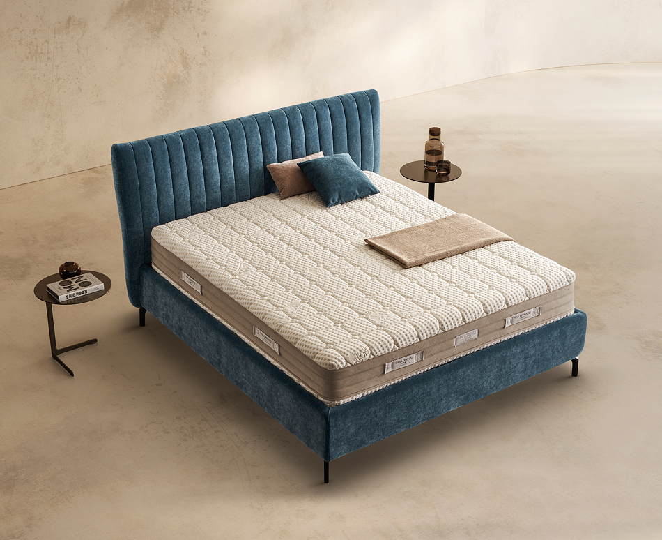 Materasso Medical Form posizionato su un letto in ambiente neutro con sopra cuscini e scaldapiedi warmie