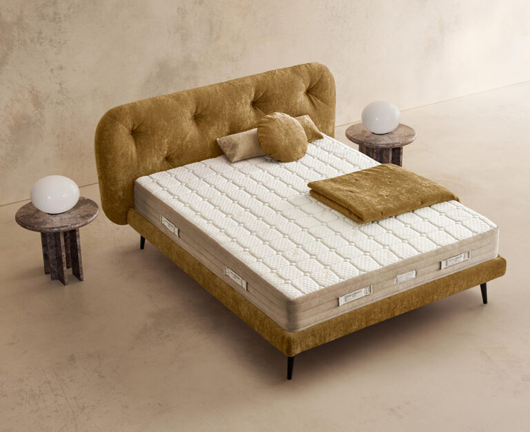 Materasso Pocket Fresh posizionato su un letto in ambiente neutro con sopra cuscini e scaldapiedi warmie