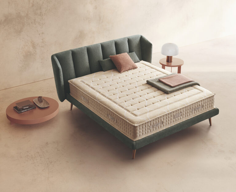 Materasso Soft Land posizionato su un letto in ambiente neutro con sopra cuscini e scaldapiedi warmie