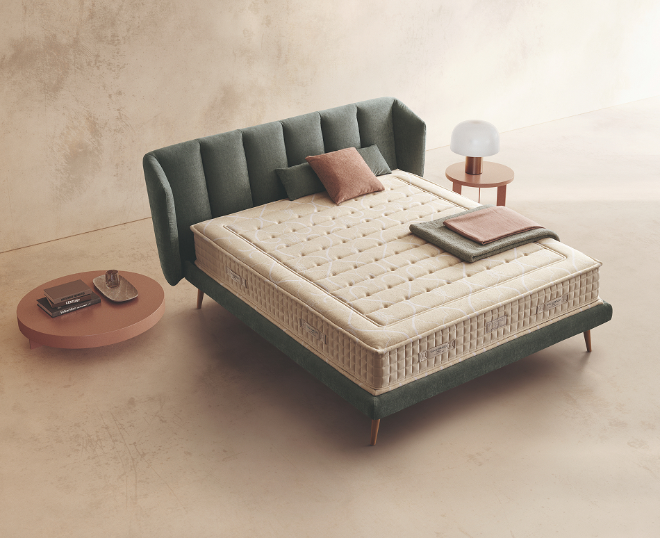 Materasso Soft Land posizionato su un letto in ambiente neutro con sopra cuscini e scaldapiedi warmie