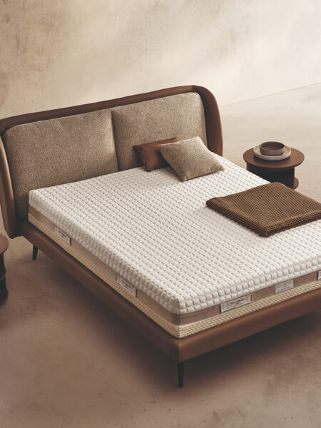 Materasso Space Memory posizionato su un letto in ambiente neutro con sopra cuscini e scaldapiedi warmie