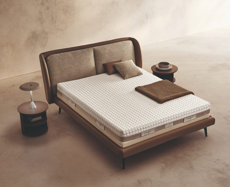Materasso Space Memory posizionato su un letto in ambiente neutro con sopra cuscini e scaldapiedi warmie