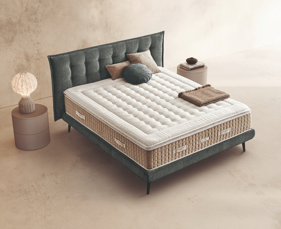 Materasso Super Topper Mind posizionato su un letto in ambiente neutro con sopra cuscini e scaldapiedi warmie