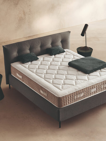 Materasso Zeus Fresh Zip posizionato su un letto in ambiente neutro con sopra cuscini e scaldapiedi warmie